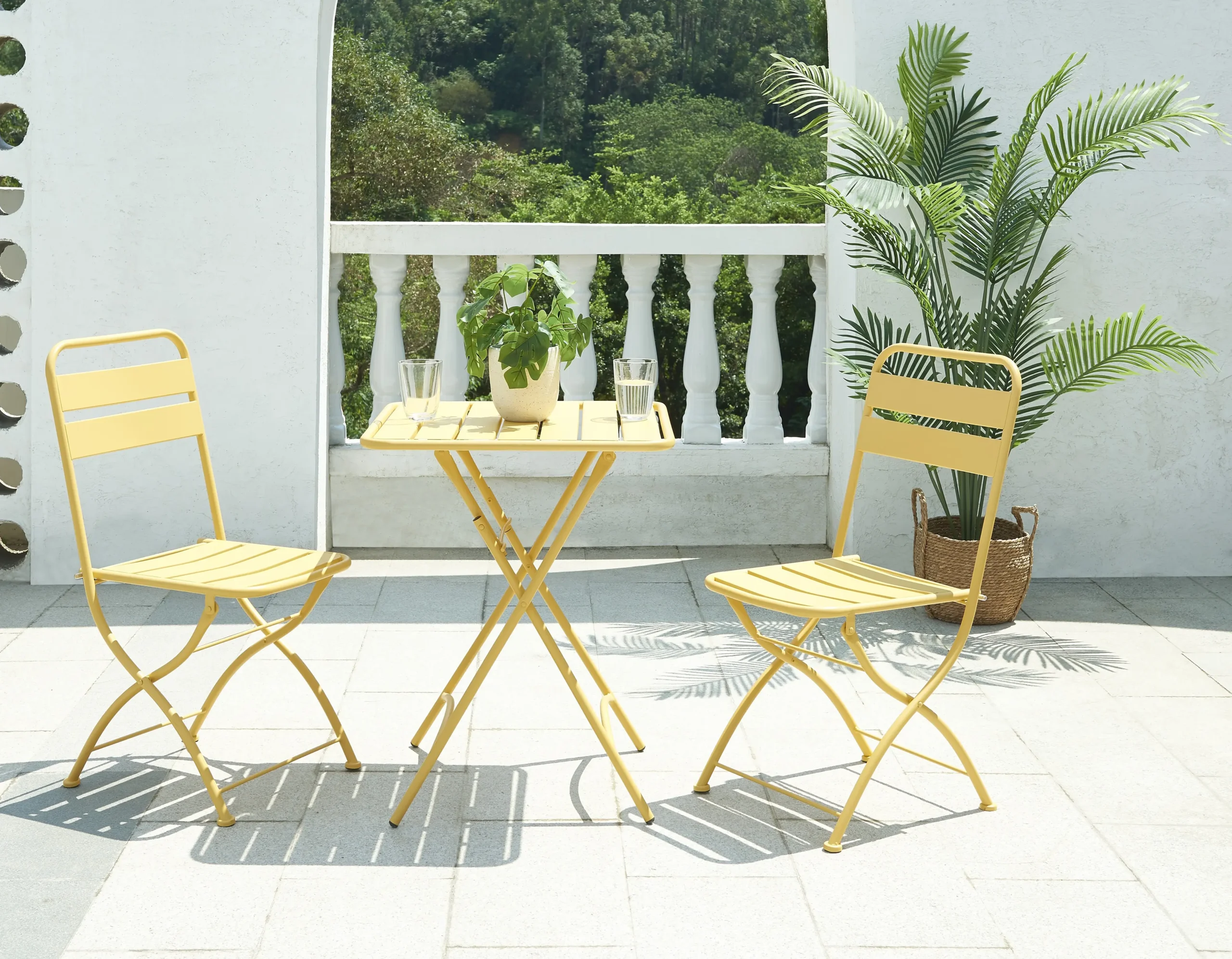 Gele opvouwbare metalen buitentafel en stoelen op een terras
